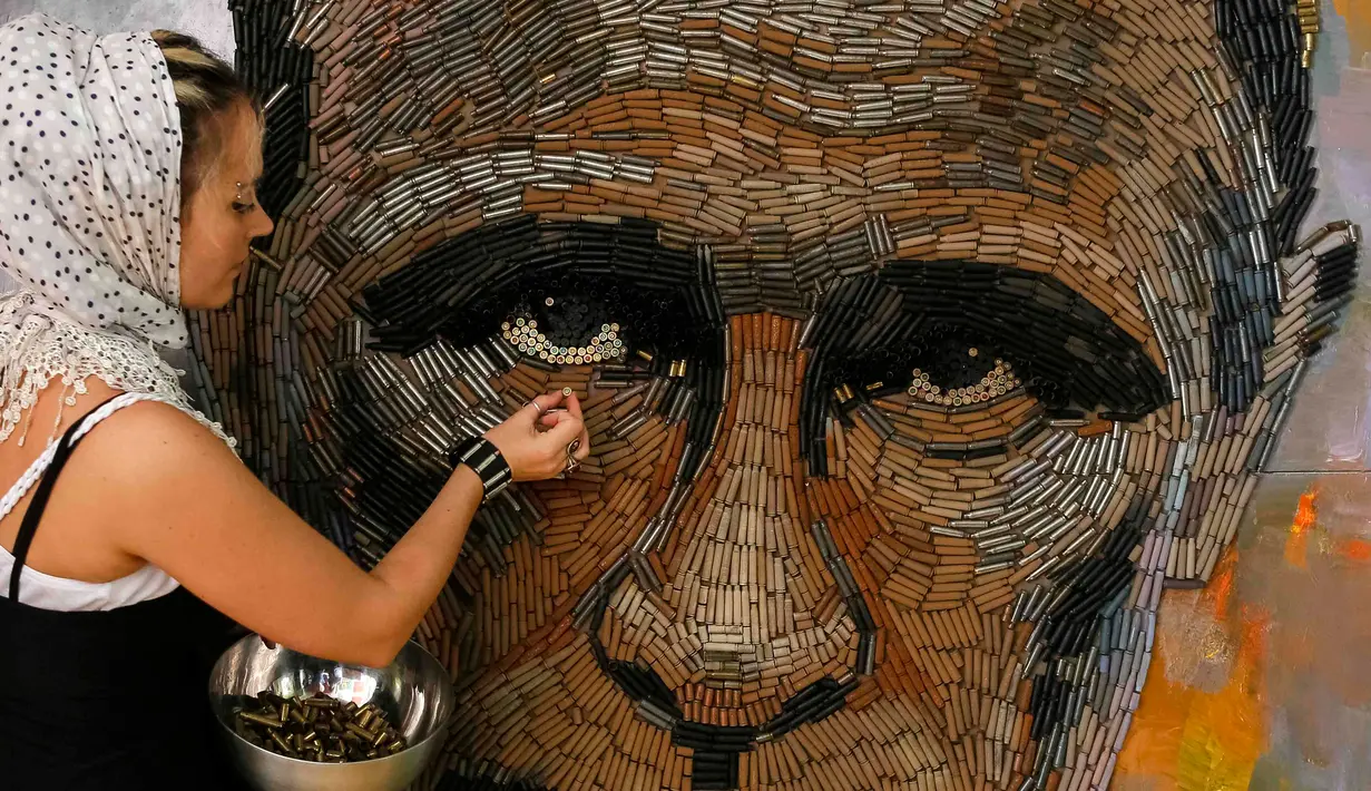 Dariya Marchenko saat membuat lukisan wajah Vladimir Putin yang dibuatnya di Kiev, Ukraina (27/7/2015). Dariya mengungkapkan peluru memiliki arti tersembunyi dan kehidupan manusia berakhir dengan kebrutalan. (REUTERS/Gleb Garanich)