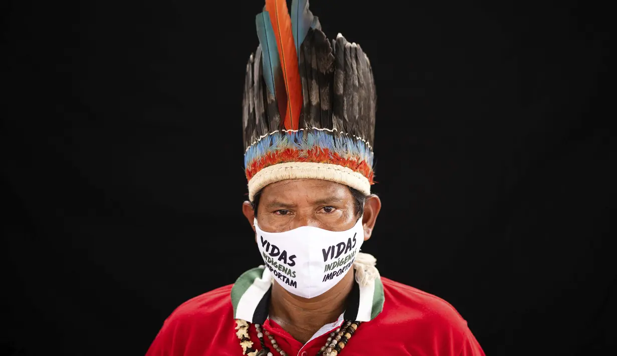 Pemimpin adat dari etnis Miranha Jose Augusto (48) mengenakan pakaian tradisional sukunya dan masker saat pandemi virus corona COVID-19 di Taman Bangsa Adat, Manaus, Brasil, Kamis (28/5/2020). Maskernya berbunyi dalam bahasa Portugis: “Kehidupan orang pribumi penting”. (AP Photo/Felipe Dana)