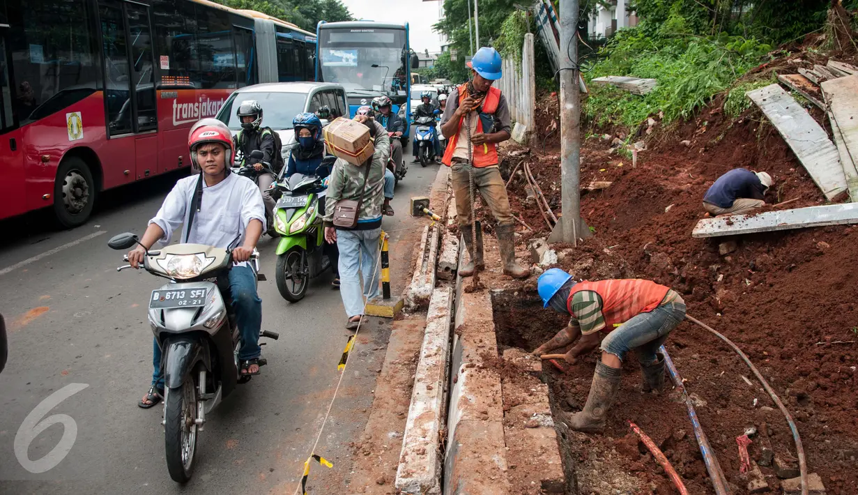 Pengendara melintas di dekat pekerja yang sedang mengerjakan proyek underpass di Jalan RA Kartini, Metro Pondok, Lebak Bulus, Jakarta, Rabu (22/3). Pembangunan underpass ini untuk mengurai kemacetan di perempatan Lebak Bulus. (Liputan6.com/Gempur M Surya)