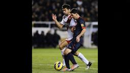 Pemain Rayo Vallecano, Jordi Amat (kiri), menjaga pergerakan dari pemain Barcelona, Lionel Messi,  dalam pertandingan lanjutan La Liga 2012/2013 yang berlangsung di stadion Vallecas, Sabtu (27/10/2012). (AFP/Pierre-Philippe Marcou)