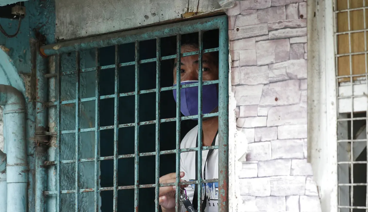 Seorang warga melihat dari dalam rumah di sebuah desa yang dilockdown untuk mencegah penyebaran COVID-19 di Manila, Filipina, Senin (15/3/2021). Kementerian Kesehatan Filipina melaporkan lonjakan kasus COVID-19 selama lebih dari seminggu. (AP Photo/Aaron Favila)