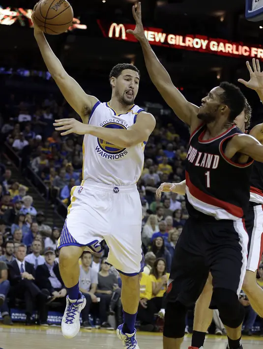 Aksi pemain Golden State Warriors, Klay Thompson (kiri) saat memberi umpan melewati hadangan pemain Blazers, Evan Turner pada laga preseason NBA basketball game, Oakland, California, Sabtu (22/10/2016) WIB. Warriors 107-96. (AP/Ben Margot)