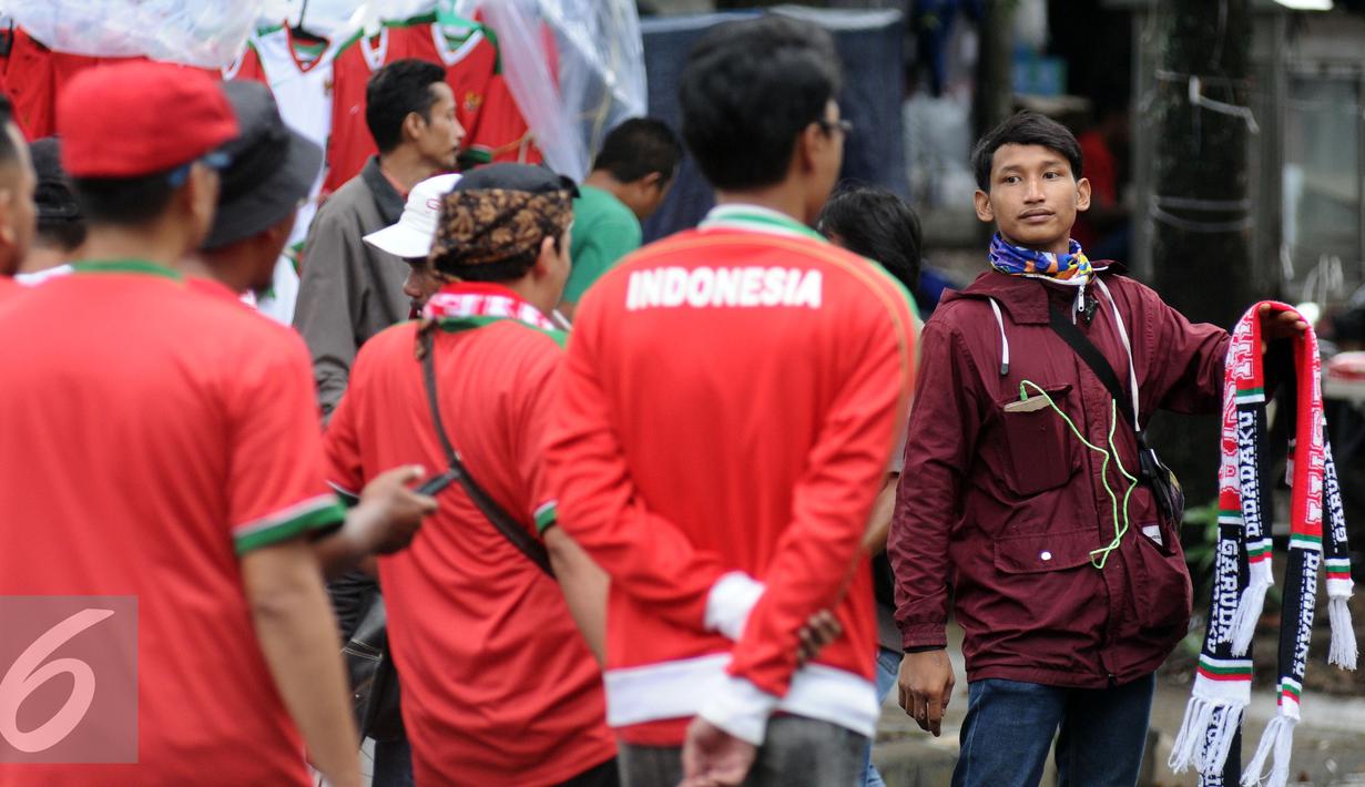 Pedagang menawarkan syal kepada suporter Timnas Indonesia di sekitar Stadion Pakansari, Bogor, Sabtu (3/12). Timnas Indonesia akan melakoni laga semifinal pertama Piala AFF 2016 melawan Vietnam. (Liputan6.com/Helmi Fithriansyah)