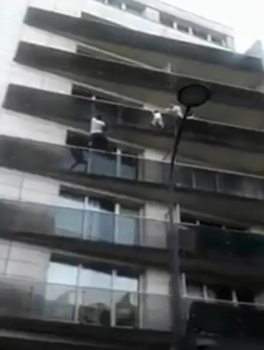 Momen ketika imigran asal Mali, Mamoudou Gassama menyelamatkan seorang balita yang nyaris jatuh dari balkon lantai empat sebuah apartemen di Paris, Prancis, Sabtu (26/5). (AP)