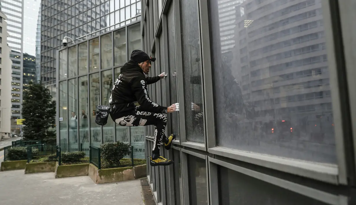 Pendaki Alain Robert atau French Spiderman mulai memanjat Menara Total di kawasan bisnis La Defense, Paris, Prancis, Senin (13/1/2020). Alain memanjat gedung tersebut tanpa menggunakan tali pengaman. (Thomas SAMSON/AFP)