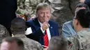 Presiden Amerika Serikat Donald Trump menunjuk sambil makan bersama para tentara di Pangkalan Udara Bagram, Afghanistan, Kamis (28/11/2019). Kunjungan dadakan Trump pada hari Thanksgiving tersebut mengejutkan pasukan AS yang bertugas di Afghanistan. (AP Photo/Alex Brandon)