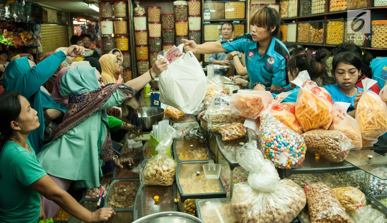 Pembeli melakukan transaksi dengan penjual kue kering di toko kue Pasar Jatinegara, Jakarta, Selasa (14/6). Pasar ini merupakan salah satu pasar kue kering yang selalu ramai diserbu para pelanggan. (Liputan6.com/Gempur M Surya)