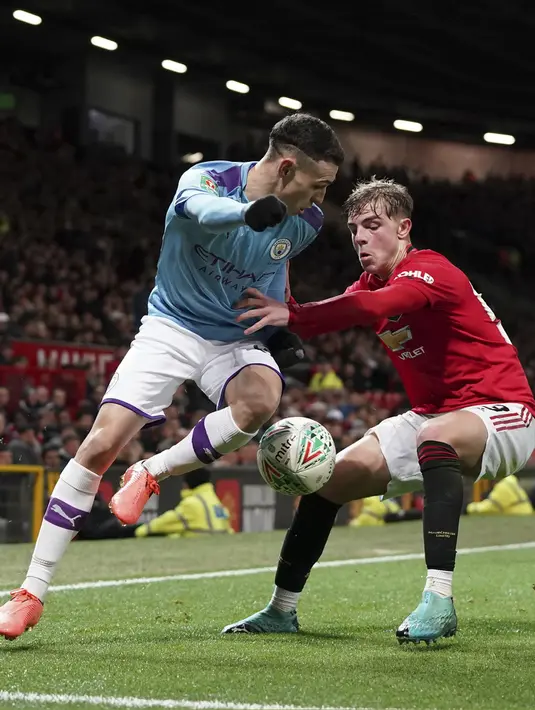 Gelandang Manchester City, Phil Foden berusaha melewati bek Manchester United, Brandon Williams pada pertandingan leg pertama semifinal Piala Liga Inggris di Old Trafford (7/1/2020). City menang 3-1 atas MU. (AP Photo / Jon Super)