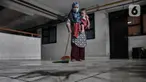 Warga saat menyapu debu batu bara yang mengotori depan rumahnya di Rusunawa Marunda, Jakarta Utara, Rabu (9/3/2022). Menurut warga rusun, pencemaran debu batu bara sudah berlangsung sejak 2019. (merdeka.com/Iqbal S. Nugroho)