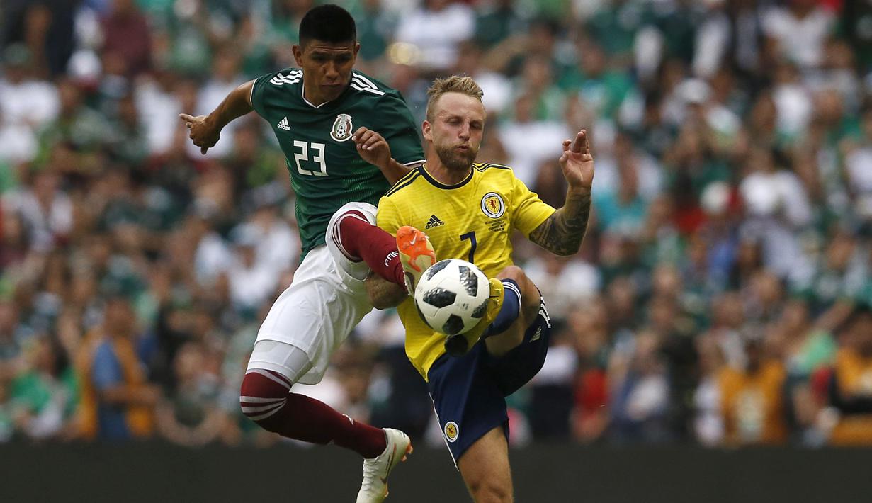 Aksi pemain Meksiko, Jesus Gallardo (kiri) berebut bola dengan pemain Skotlandia, Johnny Russell pada laga uji coba di Azteca Stadium, Meksiko City, (2/6/2018). Meksiko menang 1-0. (AP/Rebecca Blackwell)