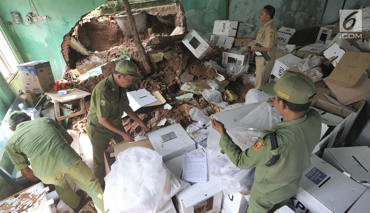 Petugas Linmas menyelamatkan kotak suara kardus yang sebagian rusak terendam banjir di gudang tempat penyimpanan logistik di Kecamatan Ciseeng, Bogor, Senin (15/4). Lebih dari 600 kotak suara rusak akibat tembok gudang jebol diterpa hujan lebat dan angin kencang semalam. (merdeka.com/Arie Basuki)