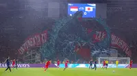 Koreografi raksasa dari suporter La Grande bergambar raksasa bergambarkan pertarungan antara Gundala dan Godzilla, serta tulisan "Untungnya Ku Tak Pilih Menyerah" di sisi kiri dan kanannya saat laga lanjutan putaran ketiga Grup C Kualifikasi Piala Dunia 2026 antara Timnas Indonesia melawan Jepang di Stadion Utama Gelora Bung Karno (SUGBK), Senayan, Jakarta, Jumat (15/11/2024). (Bola.com/Bagaskara Lazuardi)