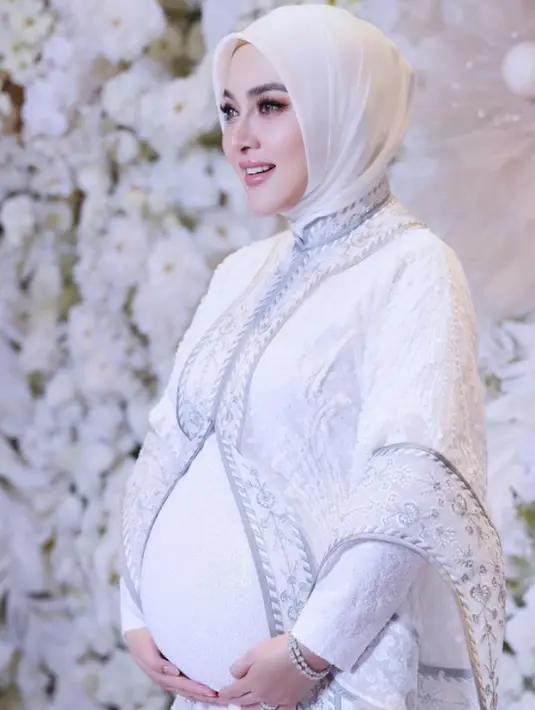 Hamil di usia 43 tahun, Syahrini pun tampil dengan pakaian serba putih. Dari inner dress lengan panjang putih dipadukan outer organza dengan embroidery putih list navy yang tampak mewah. 
 [@princessyahrini]