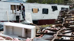 Dua orang pria memperbaiki tempat tinggal mereka yang rusak usai diterjang badai di Elon, Virginia (16/4). Akibat badai ini sejumlah rumah rusak berat. (Jay Westcott/The News & Advance via AP)