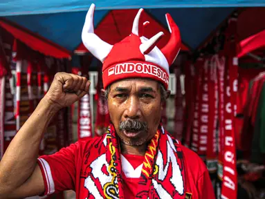 Pedagang mengenakan atribut timnas Indonesia jelang pertandingan AFF 2022 antara Indonesia melawan Thailand di Stadion Gelora Bung Karno, Jakarta, Kamis (29/12/2022). Atribut timnas Indonesia seperti kaos, syal, dan topi dijual dengan kisaran harga Rp35.000 hingga Rp75.000. (Liputan6.com/Faizal Fanani)