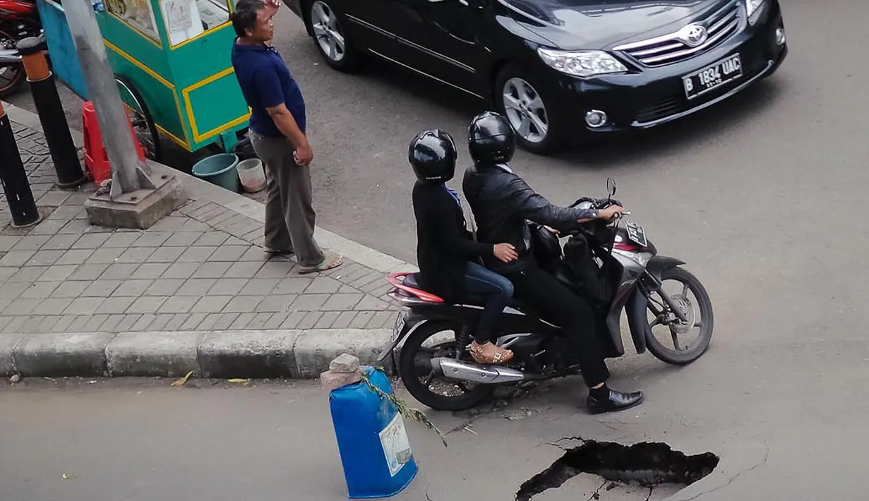 Salah satu pengendara motor menghindari ruas jalan yang amblas di depan Wisma Bakrie di kawasan Kuningan, Jakarta, (12/8/2014). (Liputan6.com/Faizal Fanani)