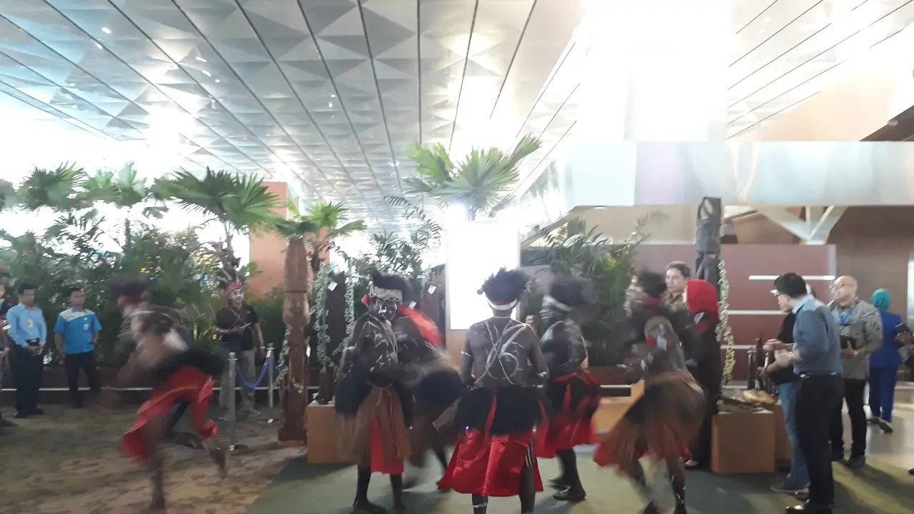 Satu keluarga turis asing terlihat foto bersama dengan Suku Kamoro, Papua di Terminal 3 Bandara Internasional Soekarno Hatta.