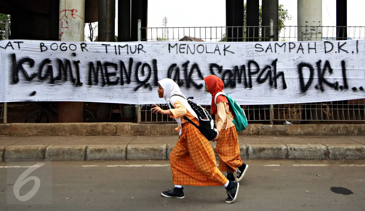Anak melintas depan spanduk penolakan sampah DKI Jakarta di Jalan Raya Narogong, Bogor Timur, Jawa Barat, Rabu (4/11/2015). Ormas bersama warga menyatakan akan tetap menolak truk sampah yang melintas di kawasan tersebut. (Liputan6.com/Immanuel Antonius)