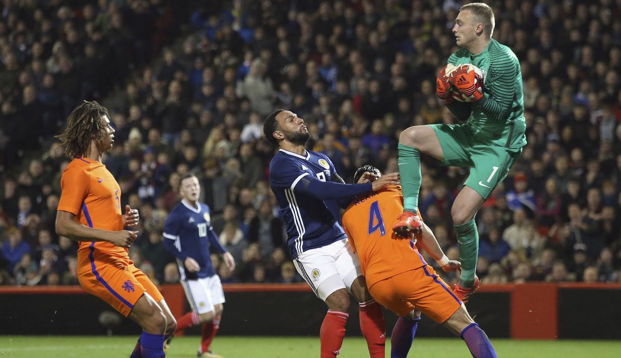 Aksi kiper Belanda, Jasper Cillessen mengamankan bola dari kejaran pemain Skotlandia pada laga persahabatan di Pittodrie, Aberdeen, Skotlandia (9/11/2017). Belanda menang 1-0. (Andrew Milligan/PA via AP)