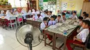 Kipas angin disediakan pihak sekolah untuk siswa sekolah dasar agar tetap sejuk di ruang kelas ditengah cuaca panas.  (AFP/CHAIDEER MAHYUDDIN)