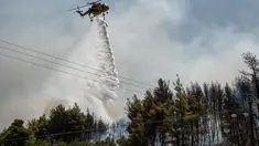Sebuah helikopter menjatuhkan air ke hutan di atas pepohonan setelah kebakaran hutan di dekat Desa Psachna di pulau Evia (Euboea), pulau terbesar kedua di Yunani, pada 27 Juli 2025. (Angelos TZORTZINIS/AFP)