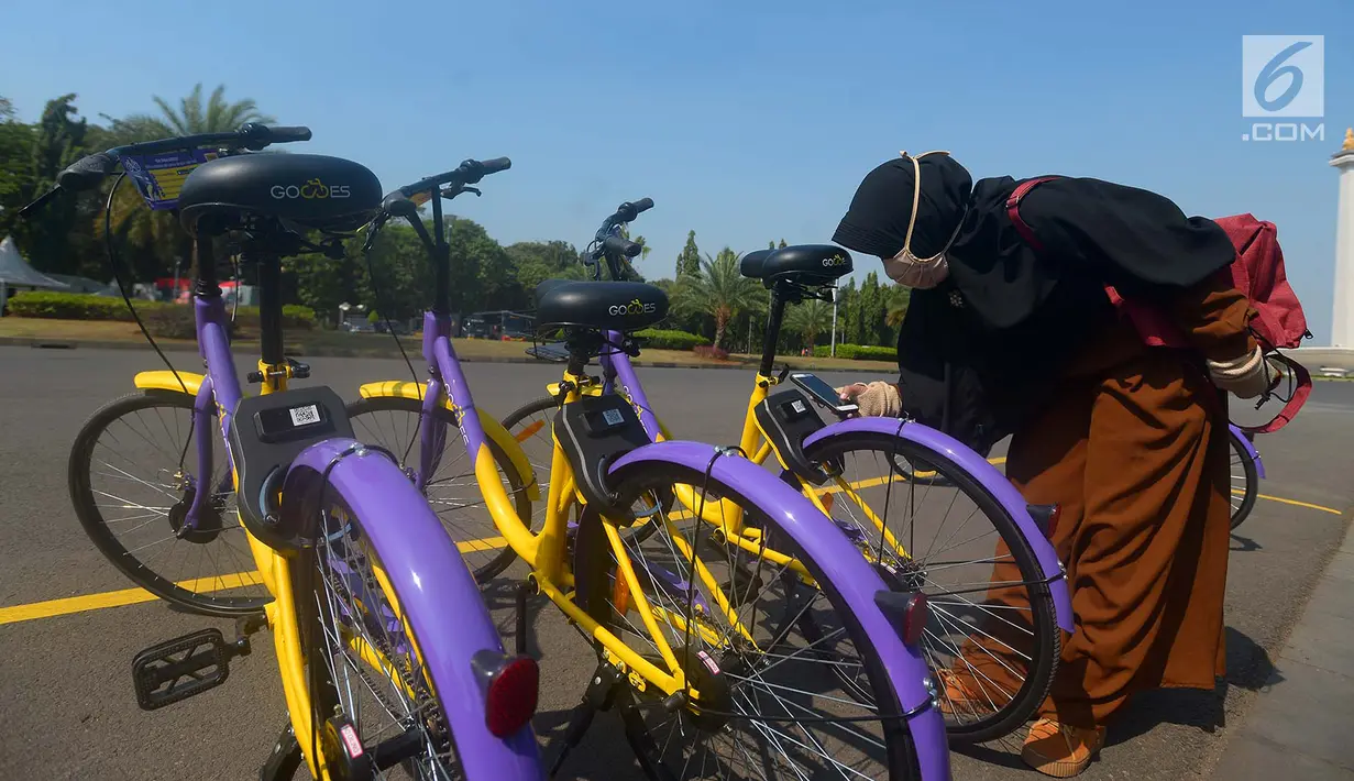 Pengunjung menscan QR Code untuk bisa menggunakan sepeda dari layanan bike sharing di Monas, Jakarta, Jumat (27/7). Layanan ini juga bertujuan mengurangi masalah emisi gas rumah kaca dan penciptaan lapangan kerja di Jakarta. (Merdeka.com/Imam Buhori)