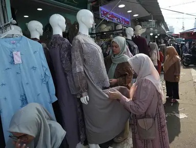 Warga berbelanja pakaian sebagai persiapan perayaan Idul Fitri di salah satu pasar musiman di Jakarta, Senin 9 Maret 2026. Pasar Tasik Cideng menjadi alternatif bagi warga Jakarta dan sekitarnya mencari pakaian khas muslim yang mengikuti tren terkini, mulai dari gamis, tunik, hingga aneka busana Lebaran berkualitas. (AP Photo/Achmad Ibrahim)
