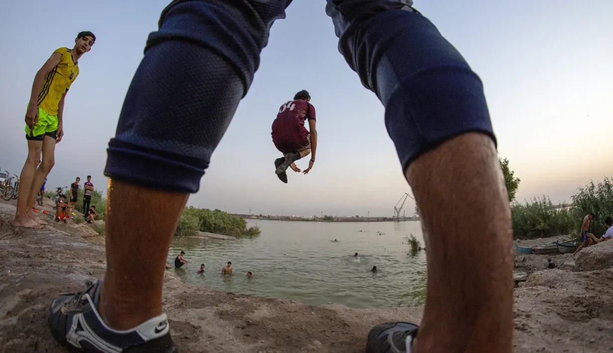 Seorang pemuda terjun ke Sungai Shatt Al-Arab di Kota Basra, Irak, Selasa (9/6/2020). Sungai yang memiliki panjang sekitar 200 Km ini menandai perbatasan antara Irak dan Iran. (Hussein FALEH/AFP)