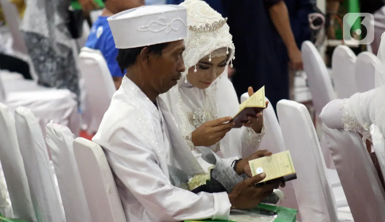 Pasangan peserta nikah massal melihat catatan buku nikah usai pelaksanaan itsbat nikah di halaman Balai Kota DKI Jakarta, Selasa (31/12/2019). Sebanyak 633 pasangan mengikuti acara nikah massal yang digelar Pemprov DKI Jakarta. (Liputan6.com/Helmi Fithriansyah)
