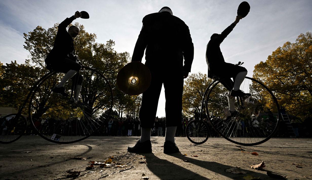 Para penggemar mengenakan pakaian bersejarah mengendarai sepeda yang mereka sebut penny-farthing, atau yang juga dikenal sebagai high wheel, dalam kompetisi tradisional 'One Mile Race' di Taman Letna, Praha, Republik Ceko, pada 1 November 2025. Para peserta lomba bersaing untuk menjadi yang tercepat atau menjadi lambat dan menjaga keseimbangan. (Michal Cizek/AFP)