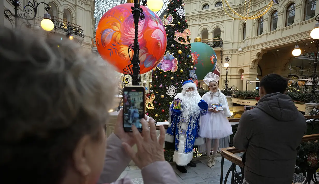 Aktor berpakaian sebagai Ded Moroz, Kakek Frost,  Sinterklas Rusia, dan Snegurochka, Gadis Salju berfoto di dalam toserba GUM, yang didekorasi untuk perayaan Natal dan Tahun Baru, di Moskow, Rusia, Rabu, 22 November 2023. (AP Photo/Alexander Zemlianichenko)