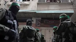 Tentara Hamas mengenakan topeng dan membawa senjata berjaga saat iring-iringan jenazah rekan mereka yang tewas di Deir el-Balah, Jalur Gaza (6/5). Hamas tidak menjelaskan lebih jauh tudingan itu. (AP/Khalil Hamra)