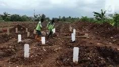 Petugas membersihkan area khusus pemakaman jenazah dengan protokol COVID-19 di TPU Srengseng Sawah Dua, Jakarta, Selasa, (2/2/2021). TPU Srengseng Sawah 2, saat ini mulai menerima pemakaman jenazah protokol COVID-19 dengan kapasitas 1.020 petak. (Liputan6.com/Helmi Fithriansyah)