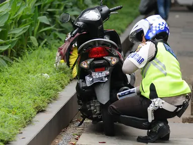 Petugas kepolisian menggembosi ban motor yang parkir di trotoar Jalan Kebon Sirih, Jakarta, Senin (17/7). Hal ini tindak lanjut maraknya pelanggaran lalu lintas di kawasan pedestrian Jalan Kebon Sirih. (Liputan6.com/Helmi Fithriansyah)