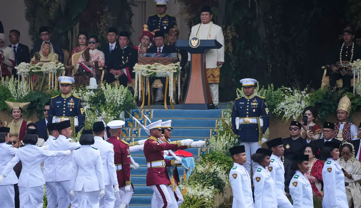 Pasukan Pengibar Bendera berbaris melewati Presiden Republik Indonesia Prabowo Subianto, di bagian atas, selama upacara pengibaran bendera memperingati ulang tahun ke-80 kemerdekaan negara di Istana Merdeka, Jakarta, Minggu 17 Agustus 2025. (AP Photo/Achmad Ibrahim)