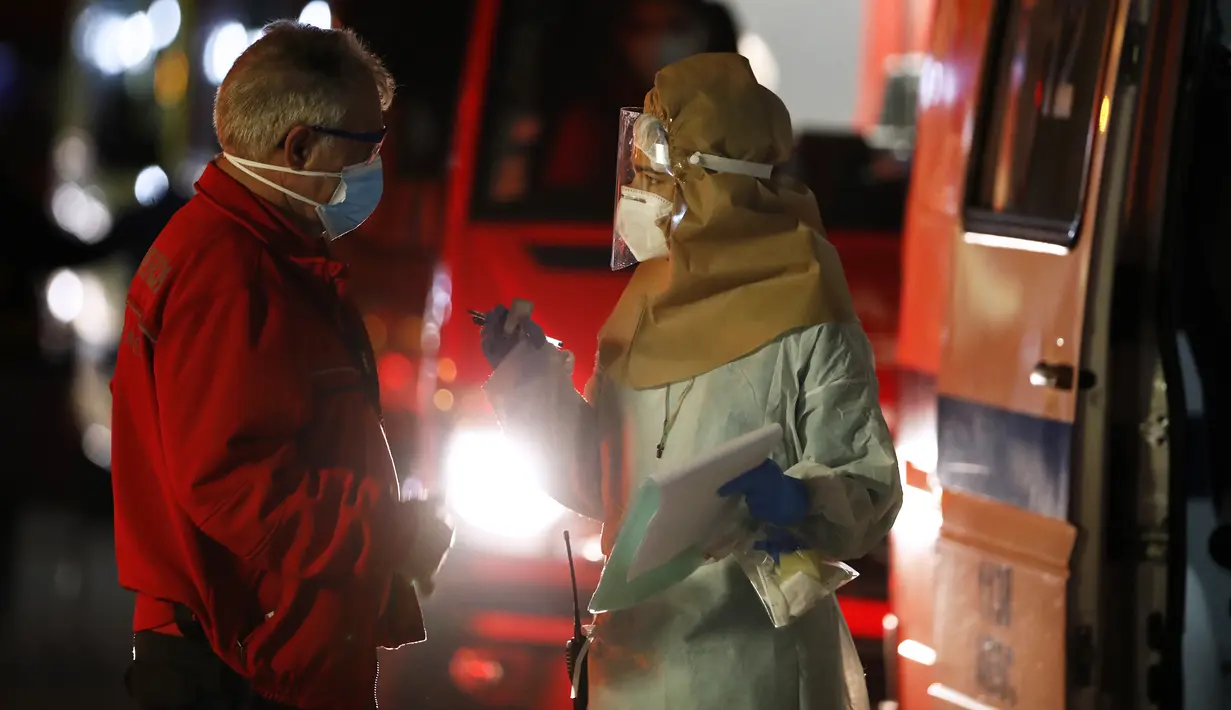 Seorang petugas medis berbicara dengan sopir ambulans yang antre untuk menyerahkan pasien COVID-19 mereka di rumah sakit Santa Maria di Lisbon, Kamis (28/1/2021). Portugal kembali mencatatkan rekor penambahan angka kasus harian virus corona dan kematian baru-baru ini. (AP/Armando Franca)