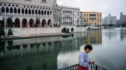 Seorang pria memakai ponselnya di luar resor kasino The Venetian, Macau, 5 Maret 2019. Pada sensus 2016, penduduk Macau berjumlah sekitar 600 ribu orang. (Anthony Wallace/AFP)