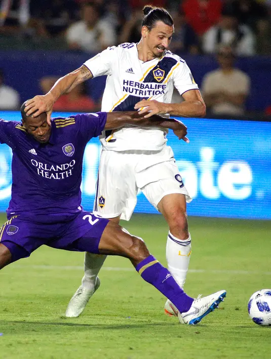 Penyerang LA Galaxy, Zlatan Ibrahimovic berusaha melewati pemain Orlando City saat pertandingan MLS di StubHub Center di Carson, California (29/7). LA Galaxy menang tipis 4-3 atas Orlando City. (AFP Photo/Katharine Lotze)