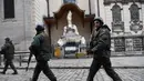 Prajurit Ukraina berjalan melewati patung-patung yang dibungkus di Katedral Latin di Lviv, 5 Maret 2022. Di tengah meningkatnya konflik antara Rusia dan Ukraina, warga kota Lviv membungkus semua patung di kota itu untuk melindungi warisan sejarahnya dari kemungkinan serangan. (Daniel LEAL/AFP)