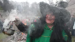 Seorang wanita mengasapi tempat menggelar ritual sihir di acara Walpurgis Night atau Witches Night di Vilnius, Lithuania, Senin (1/5). Orang-orang yang hadir mengenakan atribut layaknya para penyihir. (AFP PHOTO / Petras Malukas)