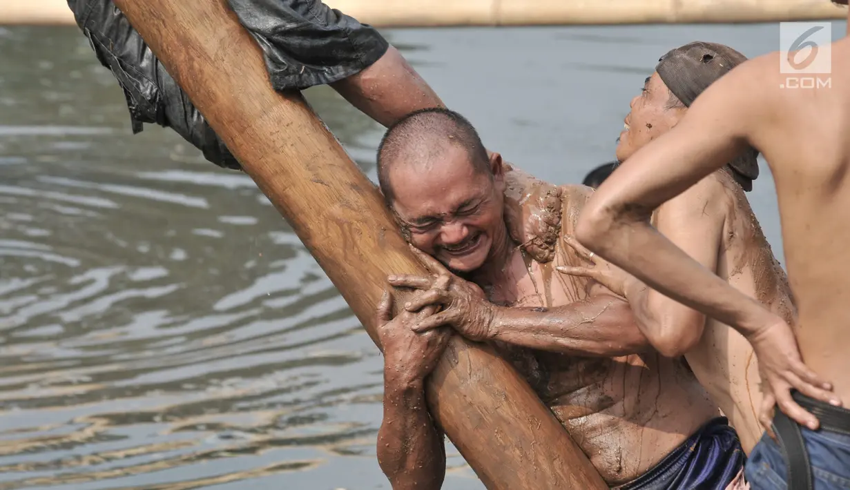 Peserta berusaha mencapai puncak saat lomba panjat pinang dalam rangka HUT ke-74 RI di Kanal Banjir Timur, Jakarta, Sabtu (17/8/2019). Lomba panjat pinang yang diikuti puluhan peserta akhirnya dapat ditaklukkan setelah lebih dari 3 jam para peserta bergelut dengan oli. (merdeka.com/Iqbal S. Nugroho)