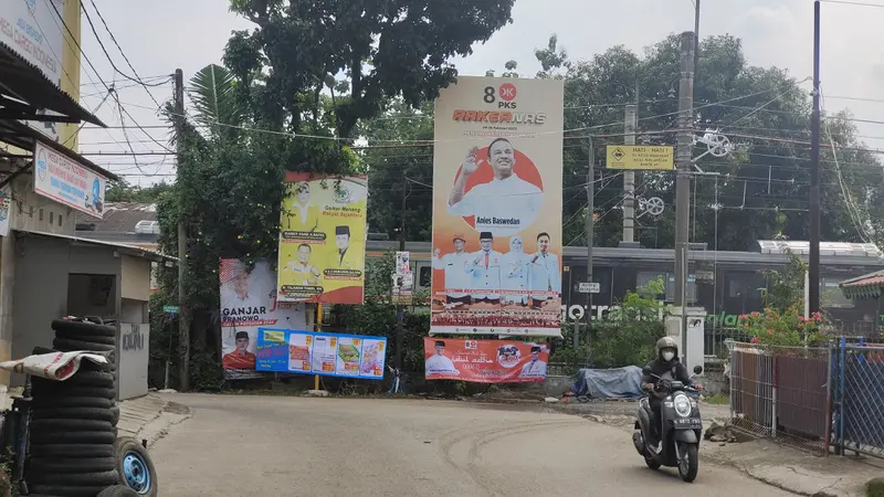 Alat peraga kampanye yang terpasang di pintu pagar pembatas milik PT KAI, Kecamatan Beji, Kota Depok.