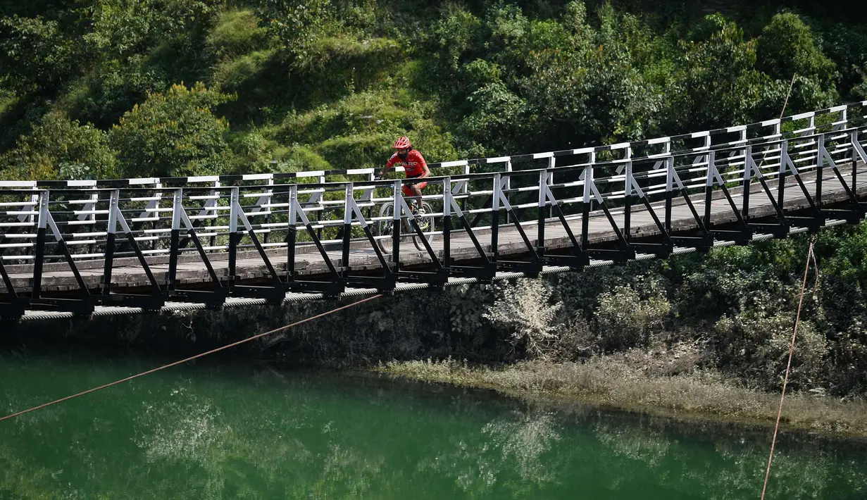 Gurman Reen Singh dari India melintasi jembatan mengikuti lomba sepeda gunung Himalaya MTB di dekat Mandi, Himachal Pradesh, India utara (4/10). Lomba sepeda ini merupakan perlombaan lintas negara tahunan ke-13. (AFP Photo/Sajjad Hussain)