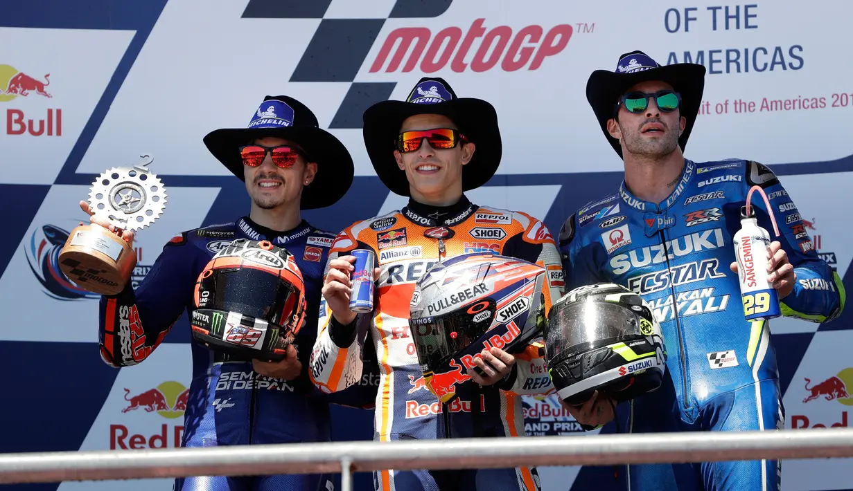 Pembalap Repsol Honda, Marc Marquez merayakan kemenangannya pada balapan MotoGP Amerika di samping Maverick Vinales dari Movistar Yamaha dan Andrea Iannone dari Suzuki Ecstar di podium Circuit of the Americas (COTA), Austin, Minggu (22/4). (AP/Eric Gay)