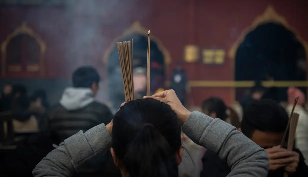 Seorang wanita berdoa untuk keberuntungan pada hari kelima Tahun Baru Imlek di Yonghegong, atau Kuil Lama di Beijing (9/2). Warga China di seluruh dunia menyambut Tahun Babi pada 5 Februari.  (AFP Photo/Nicolas Asfouri)