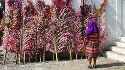 Seorang wanita melihat daun kelapa yang dihias bunga saat festival tahunan Panchimalco Flower and Palm Festival di Panchimalco, San Salvador (6/5). (AFP/Marvin Recinos)