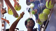 Petenis asal Prancis, Jo-Wilfried Tsonga usai membubuhkan tanda tangan di bola tenis penggemarnya setelah memenangkan pertandingan putaran kedua Australia Terbuka melawan petenis Serbia Dusan Lajovic di Melbourne, Rabu (18/1). (AP Photo/Andy Brownbill)
