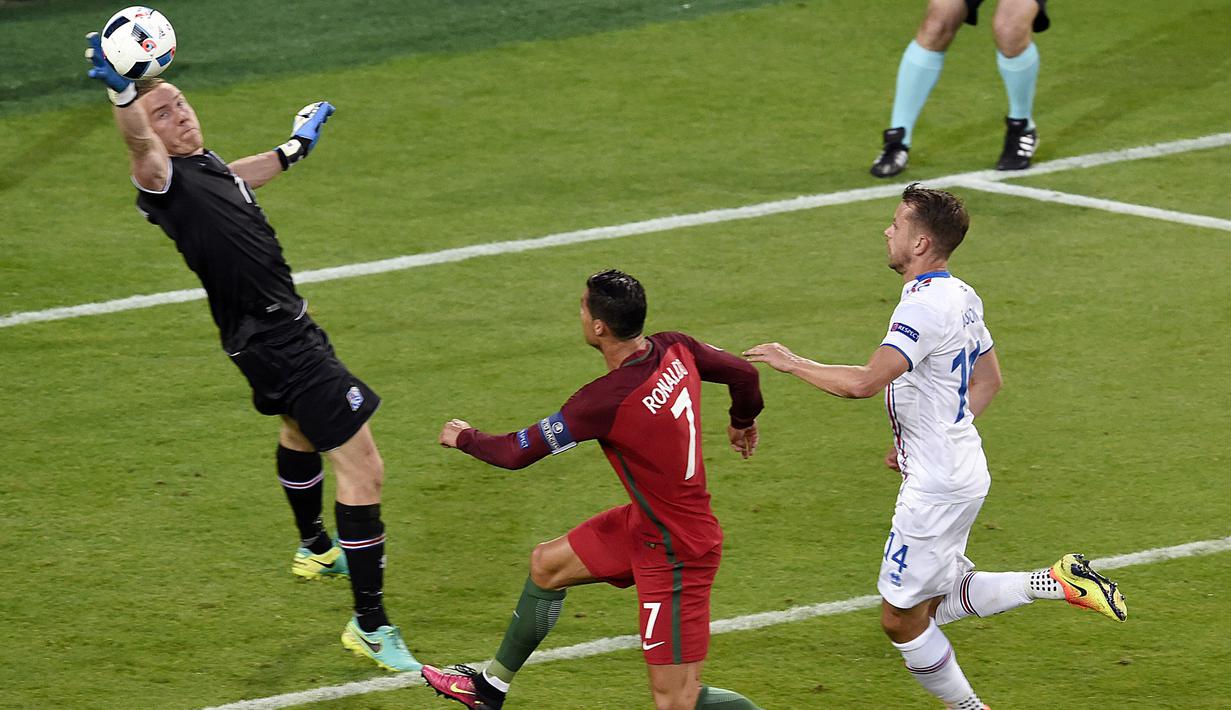 Kiper Islandia, Hannes Halldersson, menepis tendangan striker Portugal, Cristiano Ronaldo, pada laga Grup F Piala Eropa di Stadion Geoffroy Guichard, St Etienne, Rabu (14/6/2016). Islandia bermain imbang 1-1 dengan Portugal. (AFP/Jean-Philippe Ksiazek)