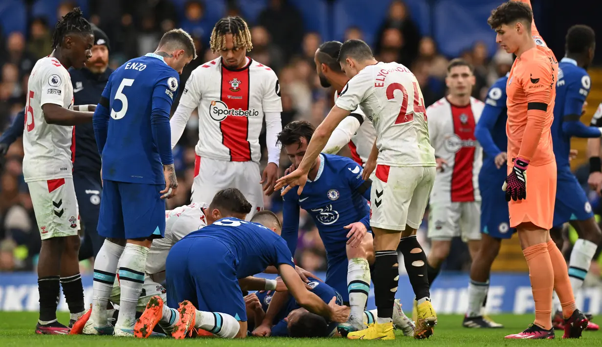 Para pemain Chelsea dan Southampton menghampiri bek Chelsea, Cesar Azpilicueta yang mengalami cedera akibat tendangan salto penyerang Southampton, Sekou Mara yang mengenai kepala selama pertandingan Liga Inggris di Stamford Bridge di London (18/2/2023). (AFP/Glyn Kirk)