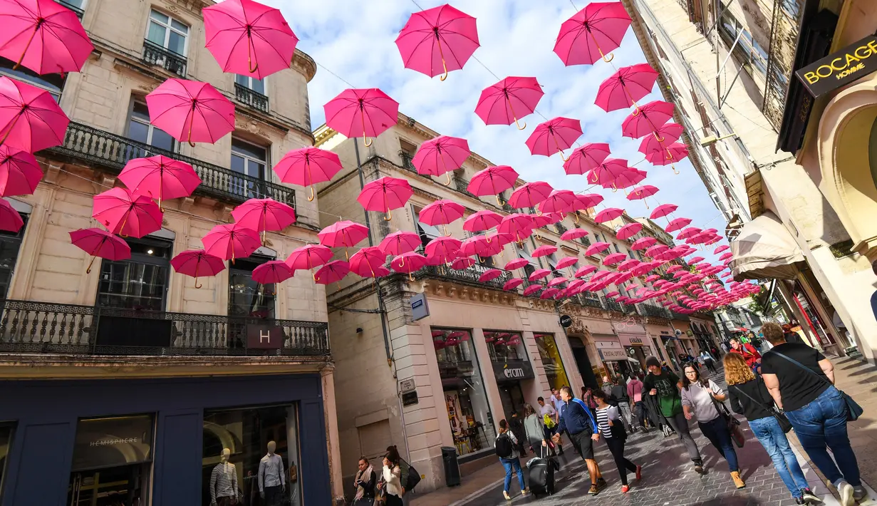 Orang-orang berjalan di bawah ratusan payung pink yang digantung untuk meningkatkan kesadaran deteksi dini kanker payudara di Montpellier, Prancis, Selasa (9/10). Bulan Oktober, ditetapkan sebagai bulan kewaspadaan atas kanker payudara. (AFP/PASCAL GUYOT)